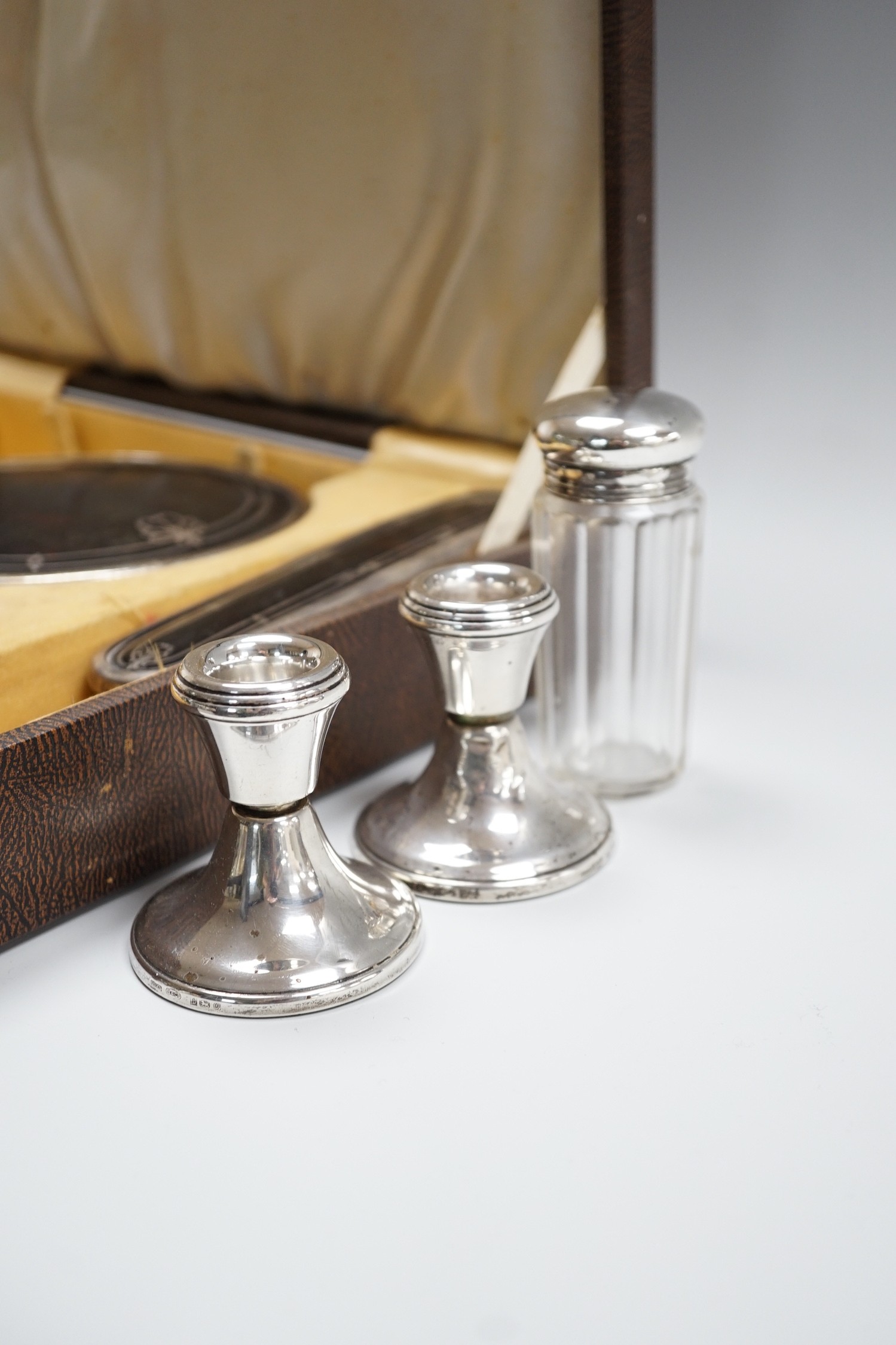 A George V cased three piece silver and tortoiseshell pique mounted mirror and brush set (lacking comb), Walker & Hall, Birmingham, 1931/37, a pair of modern silver mounted dwarf candlesticks and a silver mounted glass t